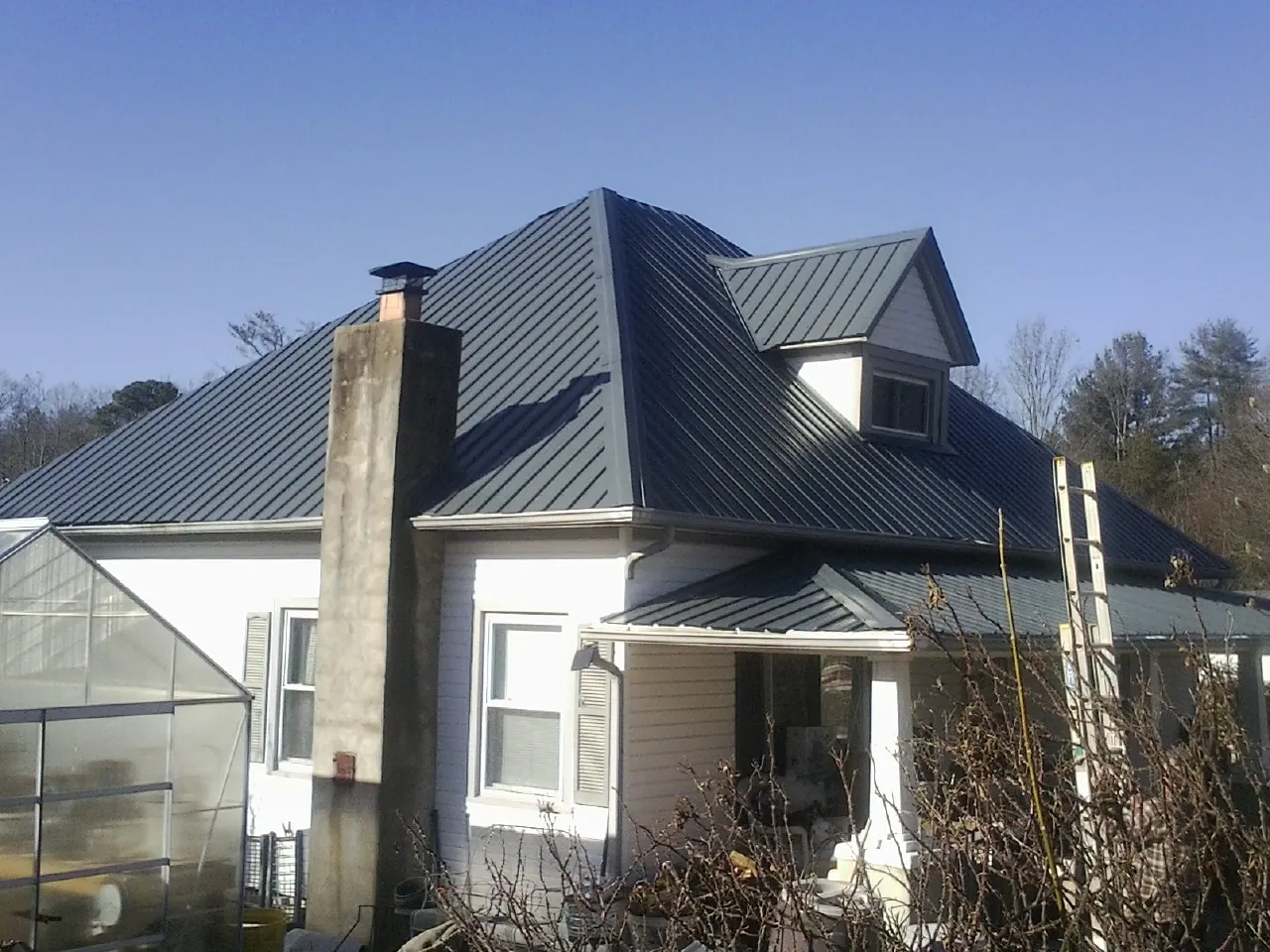 Dark blue standing seam metal roof on a white farmhouse with dormer — Slate & Tile Roof Repair by Roofing Brothers in Enumclaw