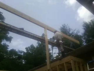 Carpenter setting a ridge beam over a new addition frame — Ice Dam Removal by Roofing Brothers in Enumclaw
