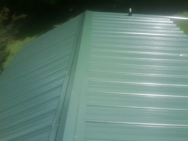 New green metal panels meeting at the ridge of a roof — Flat Roof Repair work by our crew in Enumclaw