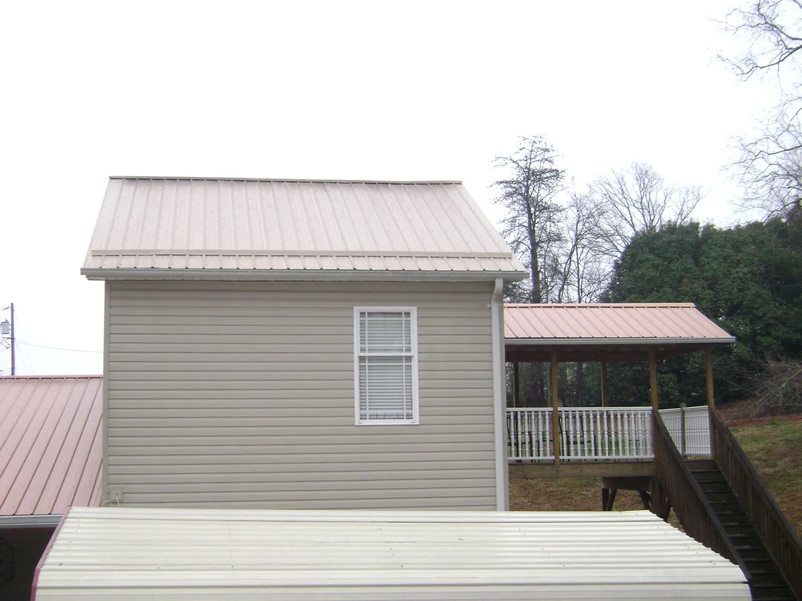 Tan metal roofs on a two story addition and attached porch, from a Roof Replacement job in Enumclaw